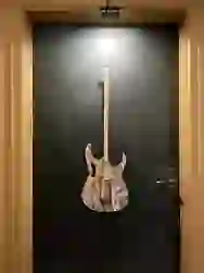 Dosengitarre im Comic-Stil hängt an einer Tür